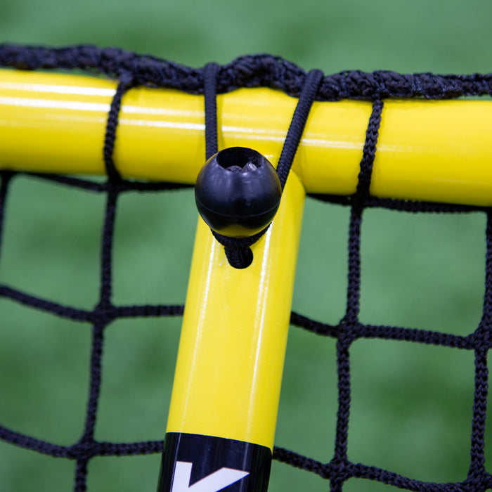 Close-up of a yellow Replacement Support Arm for Keeper Goals Folding Aluminum Soccer Goal, securing a black net with a cord and plastic fastener, set against a blurred green background.